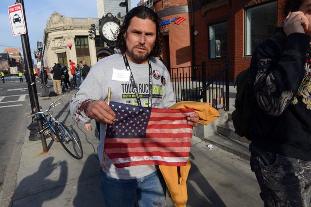 Carlos Arredondo, who was at the finish line of the 117th Boston Marathon when two explosives detonated, leaves the scene with a bloodied American flag